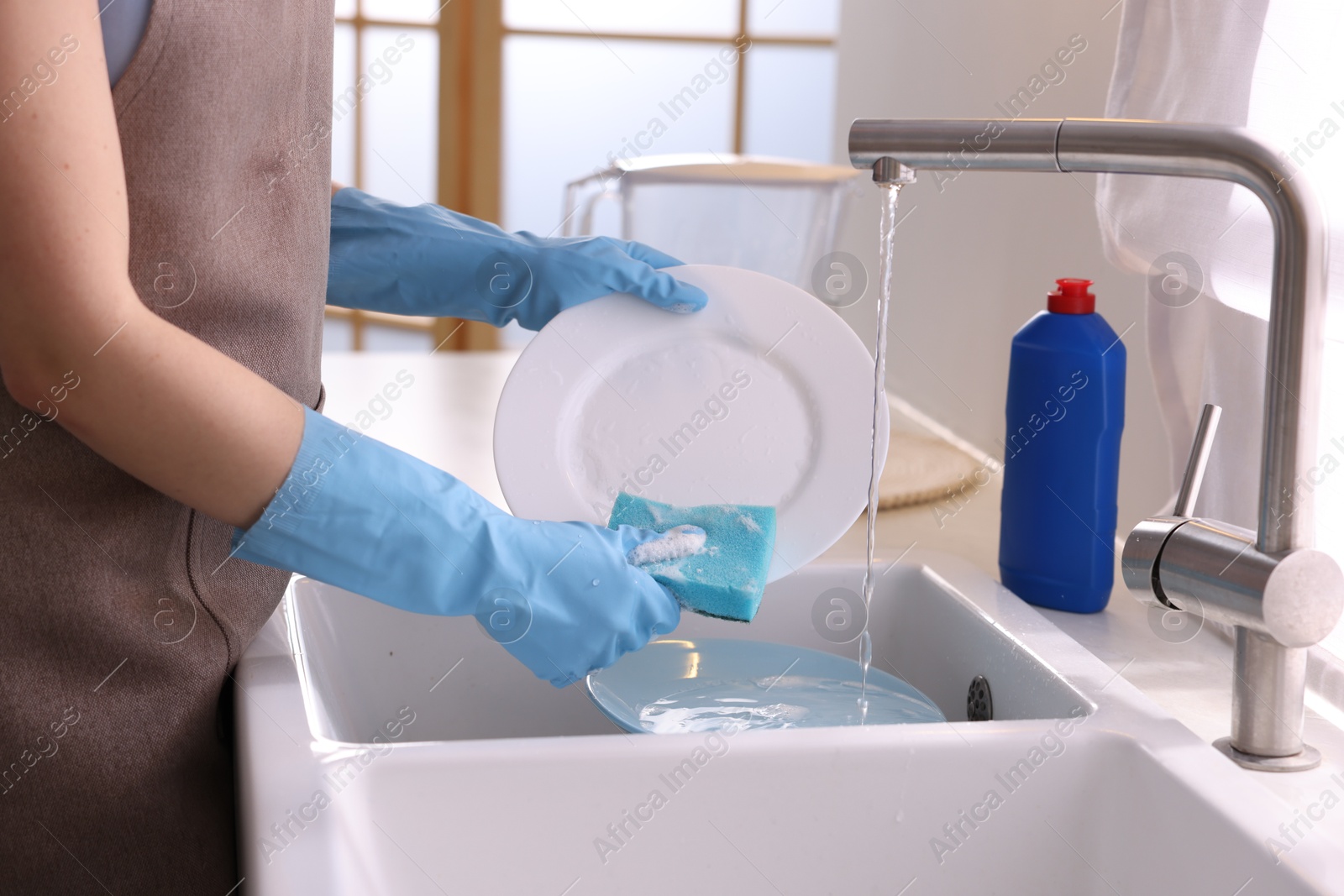 Photo of Woman washing dishes in kitchen sink, closeup