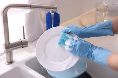 Photo of Woman washing dishes in kitchen sink, closeup