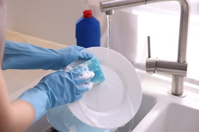 Photo of Woman washing dishes in kitchen sink, closeup