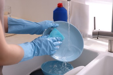 Photo of Woman washing dishes in kitchen sink, closeup