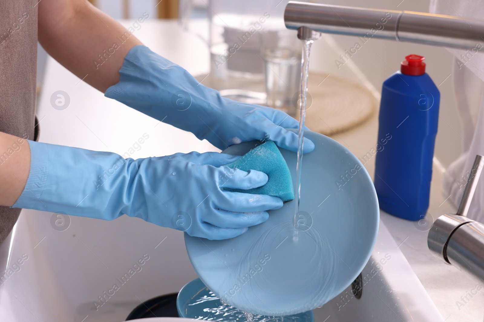 Photo of Woman washing dishes in kitchen sink, closeup