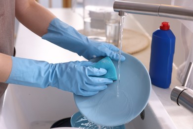 Photo of Woman washing dishes in kitchen sink, closeup