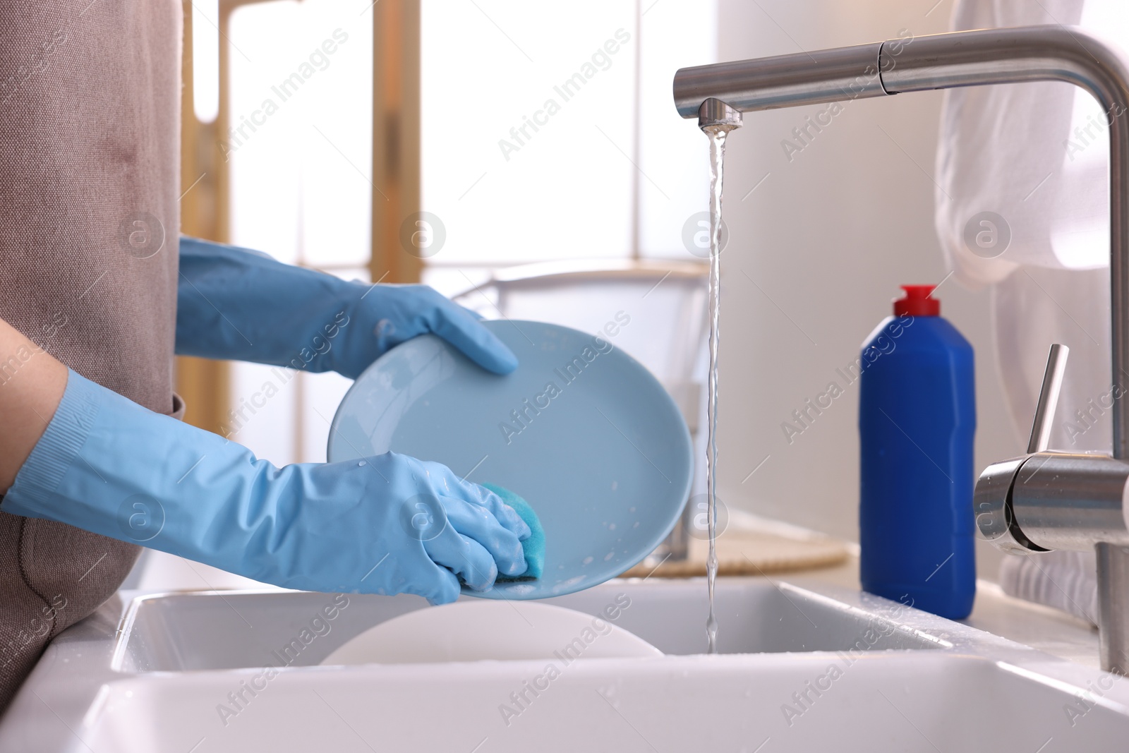 Photo of Woman washing dishes in kitchen sink, closeup