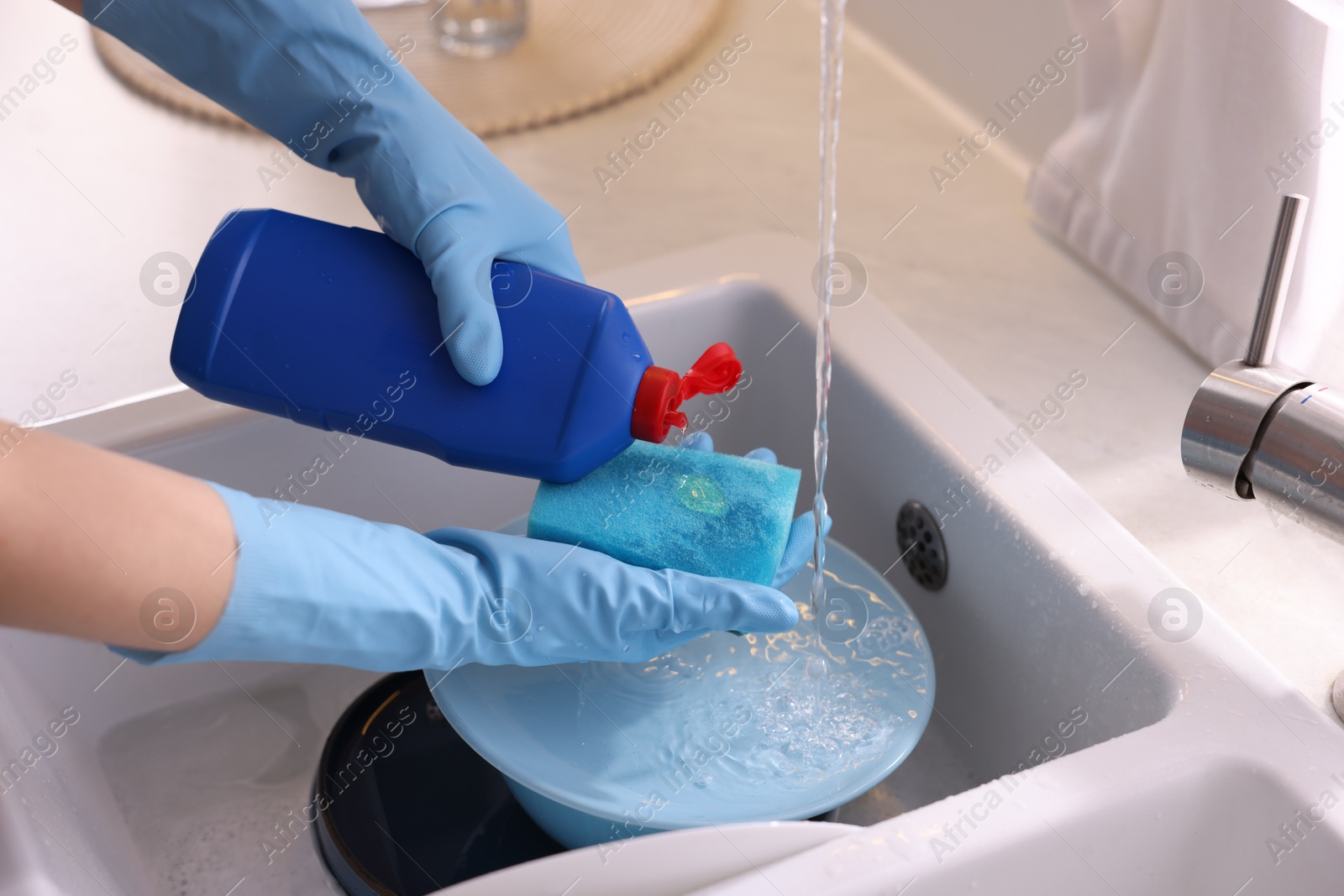 Photo of Woman washing dishes in kitchen sink, closeup