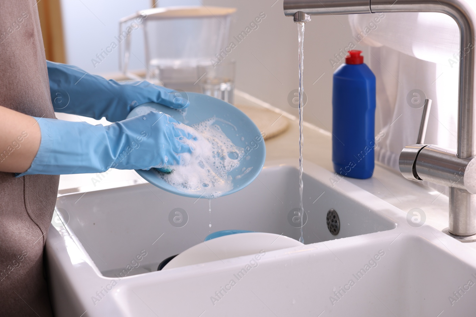 Photo of Woman washing dishes in kitchen sink, closeup