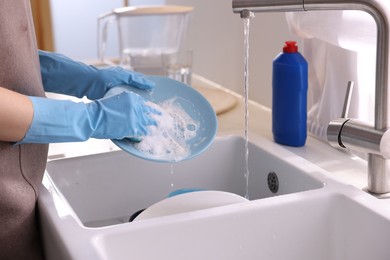 Photo of Woman washing dishes in kitchen sink, closeup