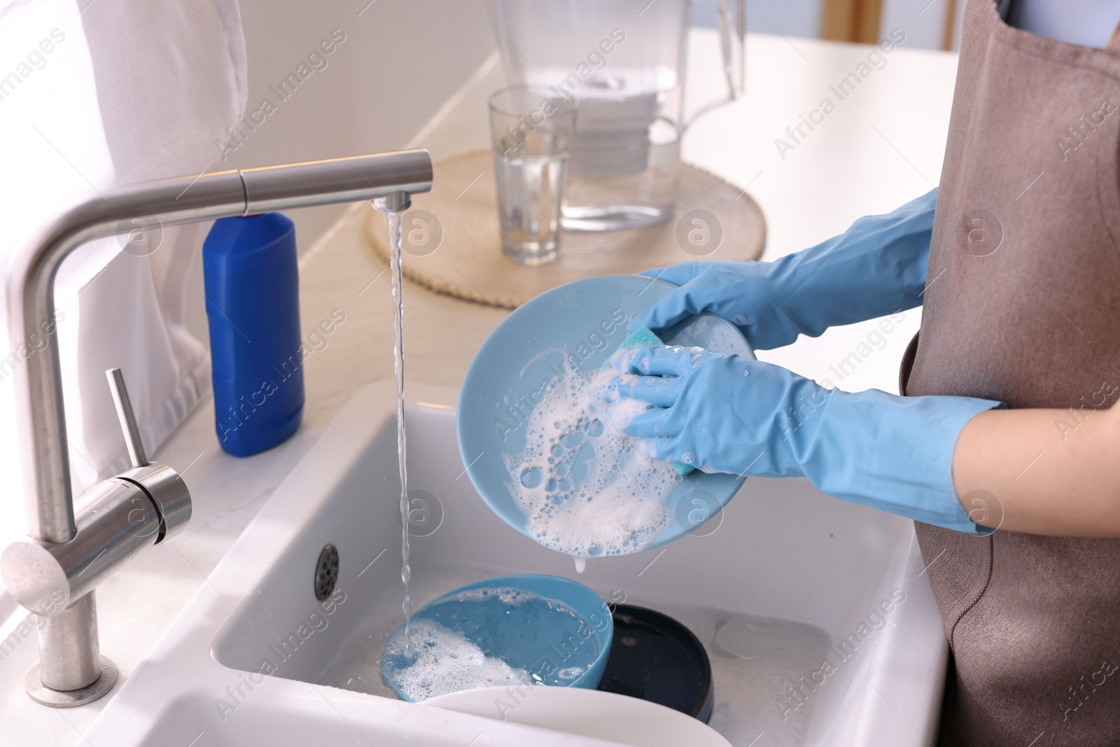 Photo of Woman washing dishes in kitchen sink, closeup