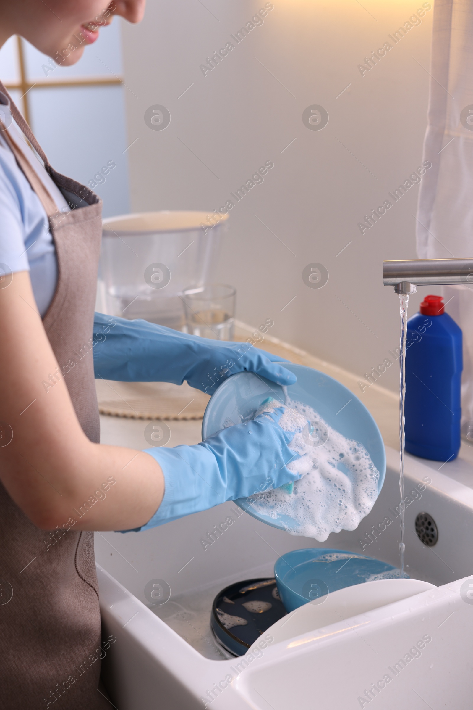 Photo of Woman washing dishes in kitchen sink, closeup