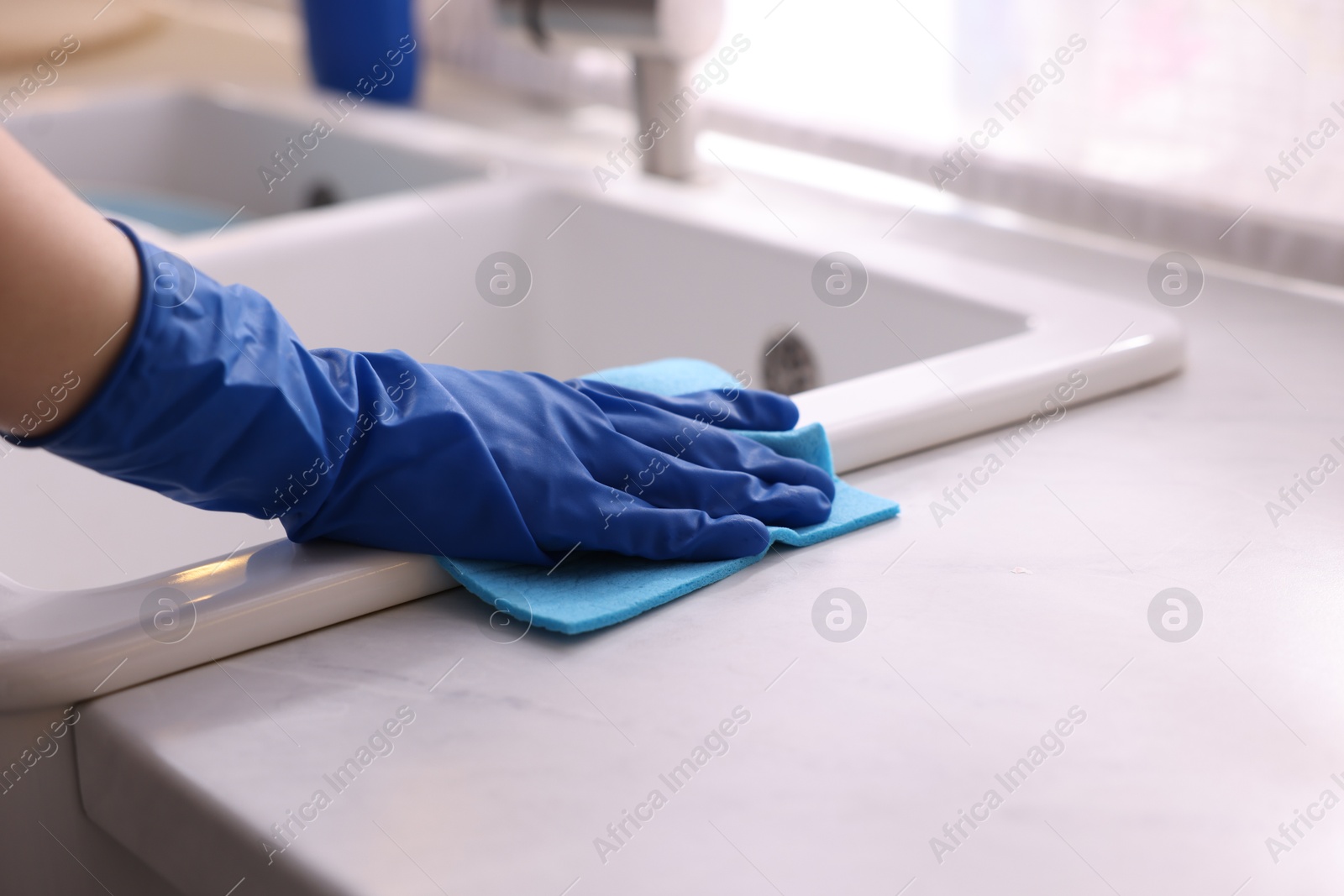 Photo of Woman wiping kitchen sink with rag indoors, closeup