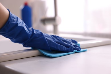 Photo of Woman wiping kitchen sink with rag indoors, closeup