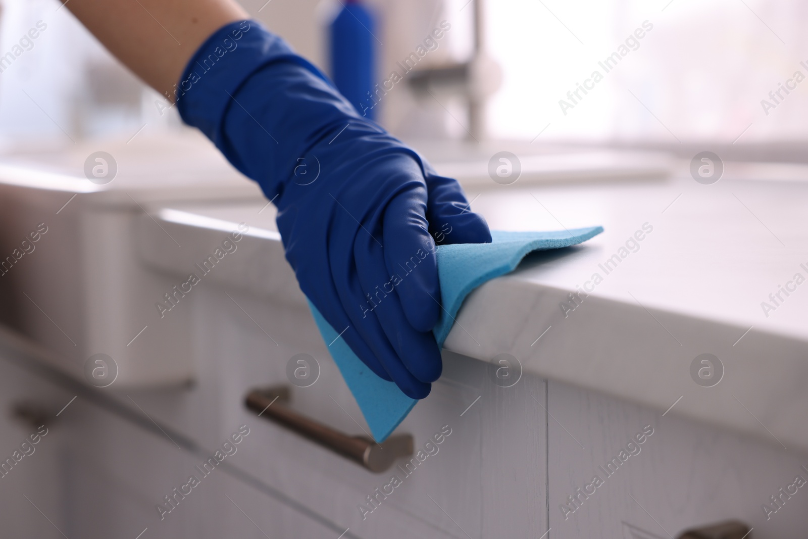 Photo of Woman wiping countertop with rag indoors, closeup