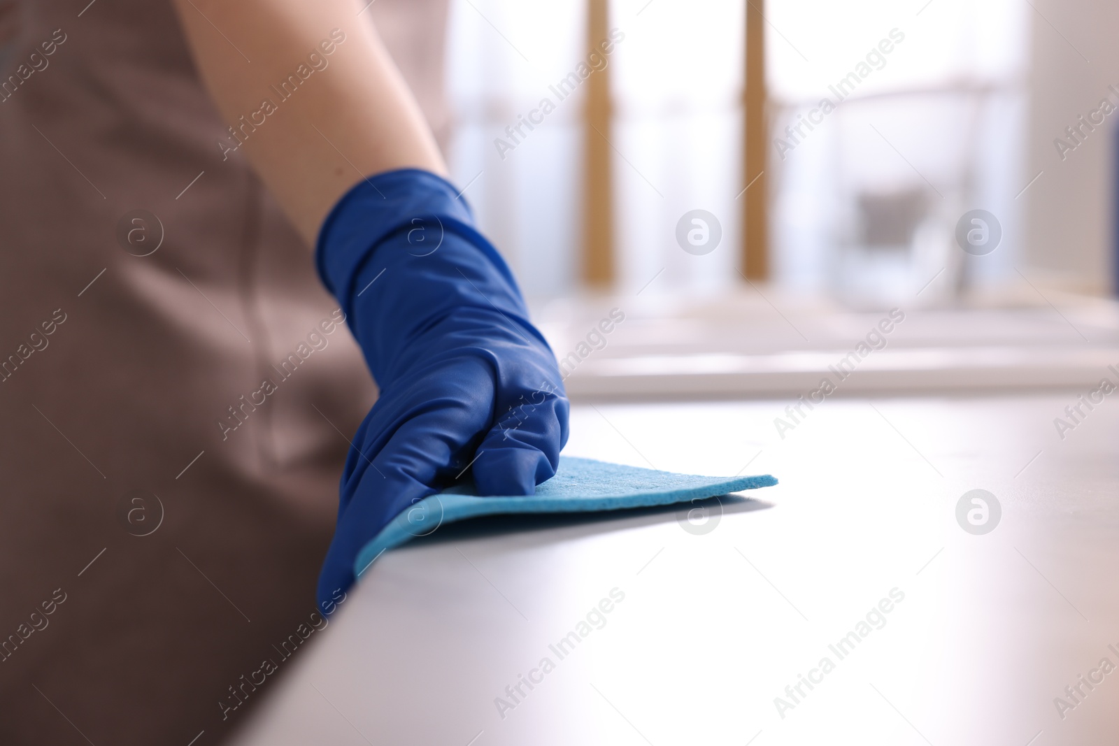 Photo of Woman wiping countertop with rag indoors, closeup