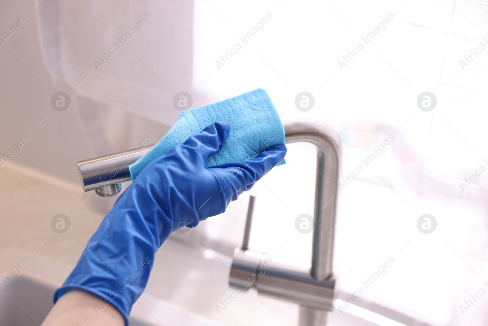 Photo of Woman wiping faucet of kitchen sink with rag indoors, closeup