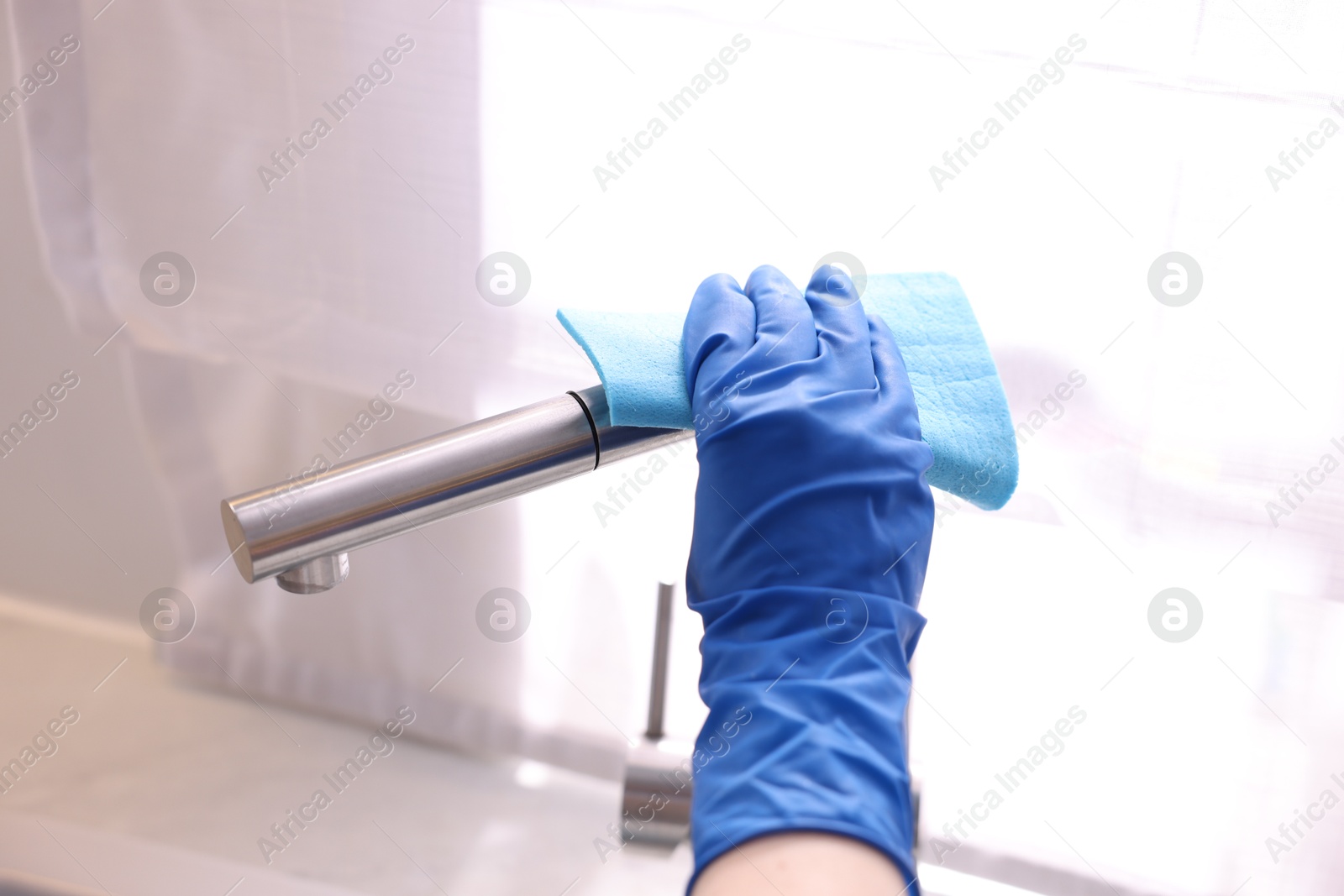 Photo of Woman wiping faucet of kitchen sink with rag indoors, closeup