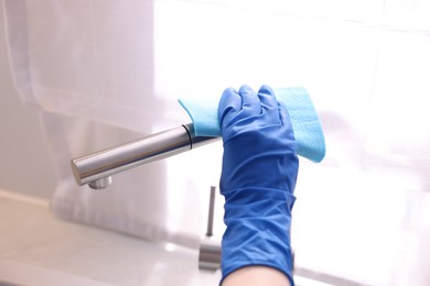 Photo of Woman wiping faucet of kitchen sink with rag indoors, closeup