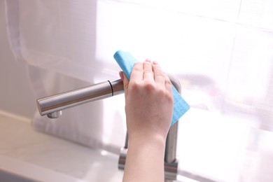 Photo of Woman wiping faucet of kitchen sink with rag indoors, closeup