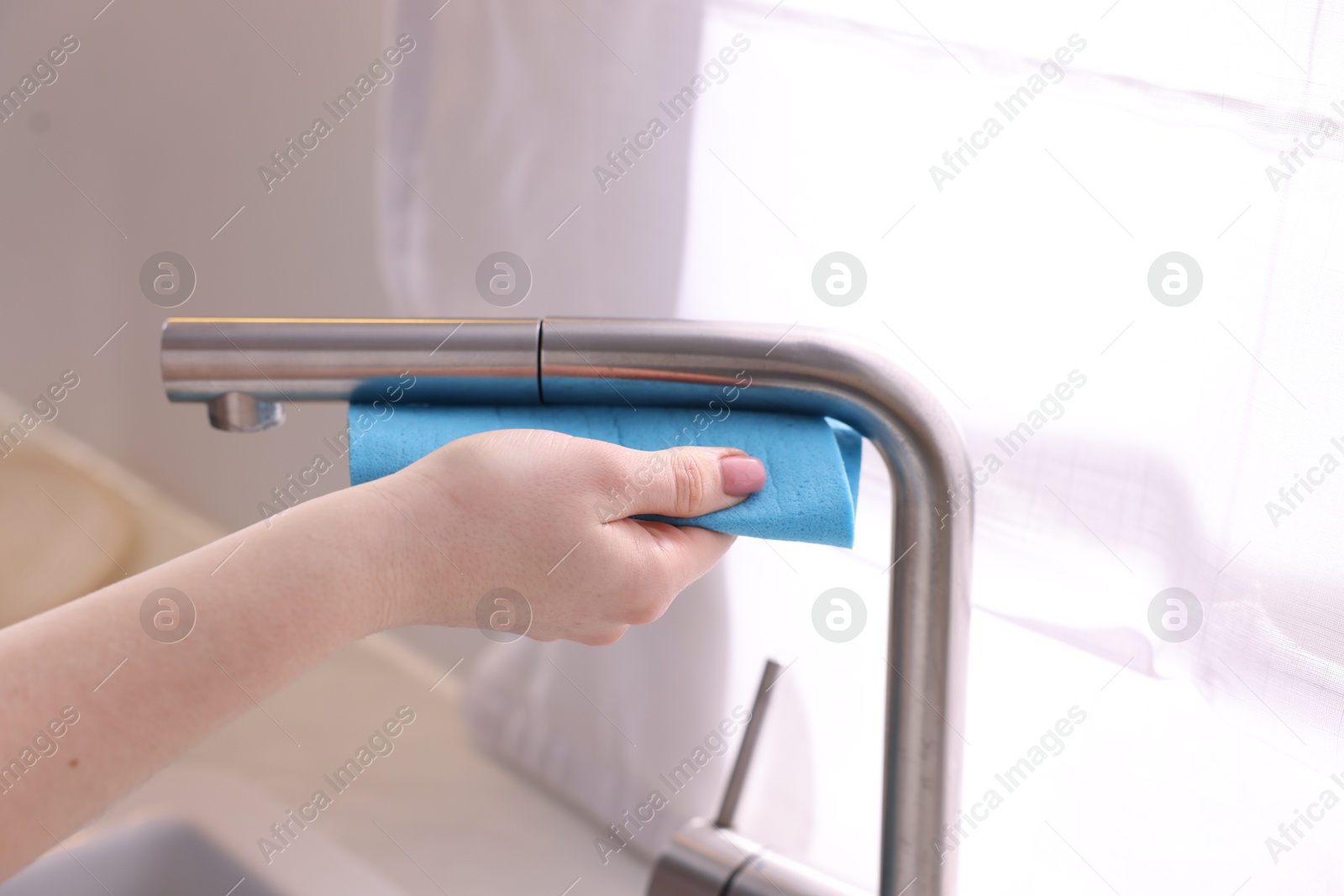 Photo of Woman wiping faucet of kitchen sink with rag indoors, closeup