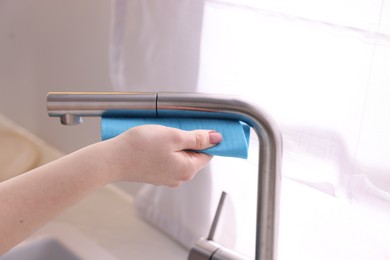 Photo of Woman wiping faucet of kitchen sink with rag indoors, closeup