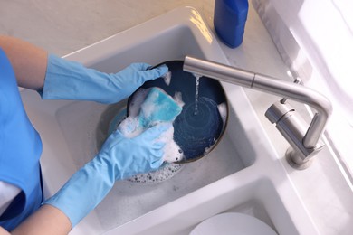 Photo of Woman washing dishes in kitchen sink, top view