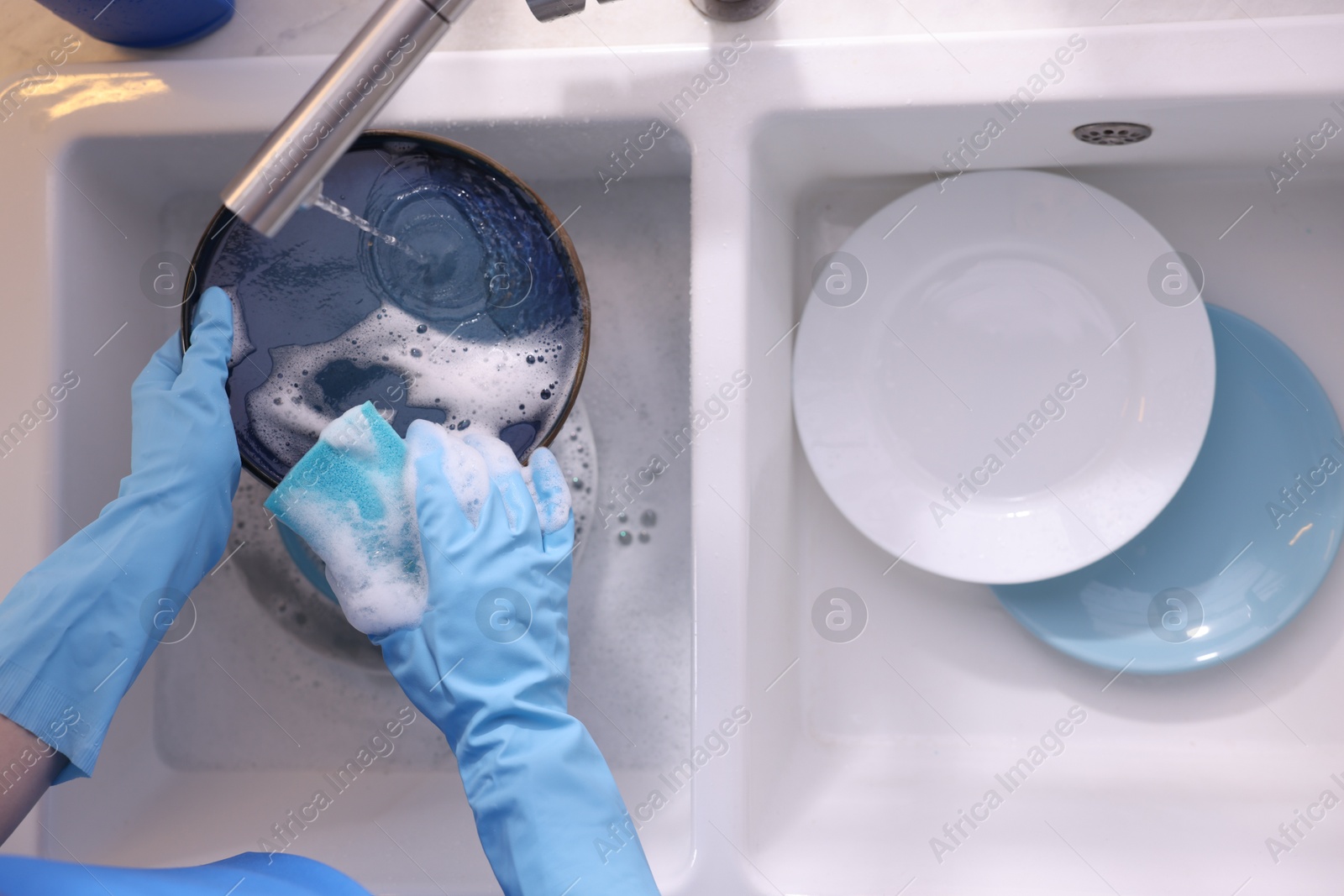 Photo of Woman washing dishes in kitchen sink, top view