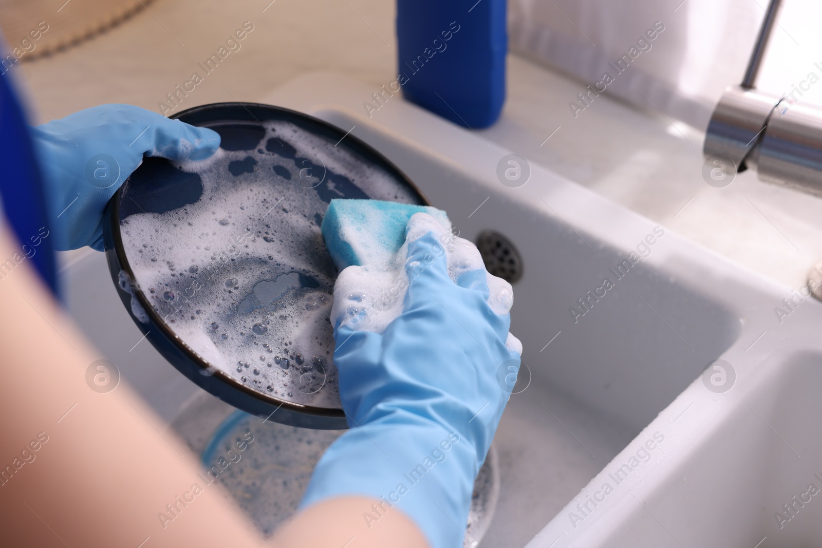 Photo of Woman washing dishes in kitchen sink, closeup