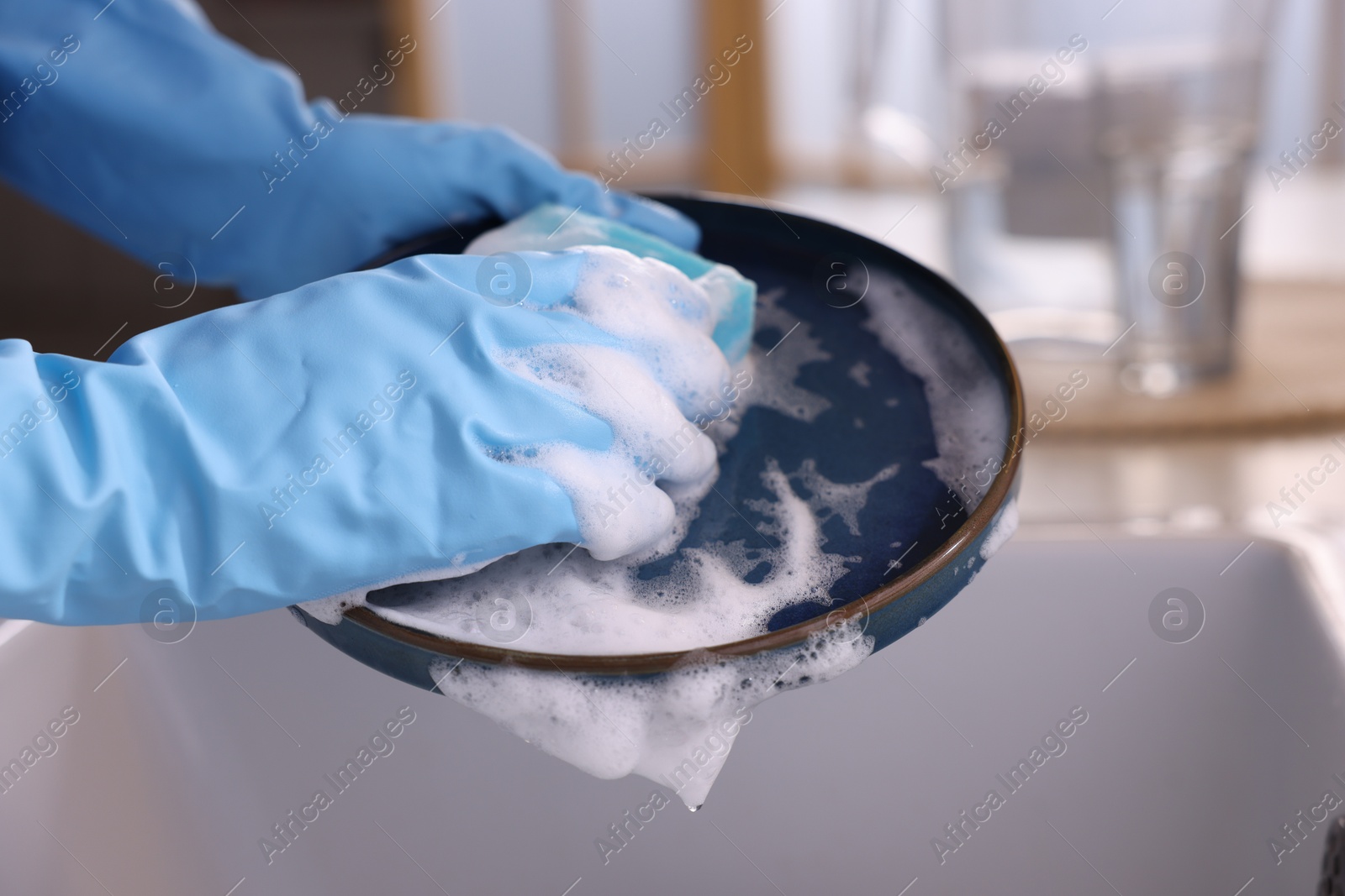 Photo of Woman washing dishes in kitchen sink, closeup