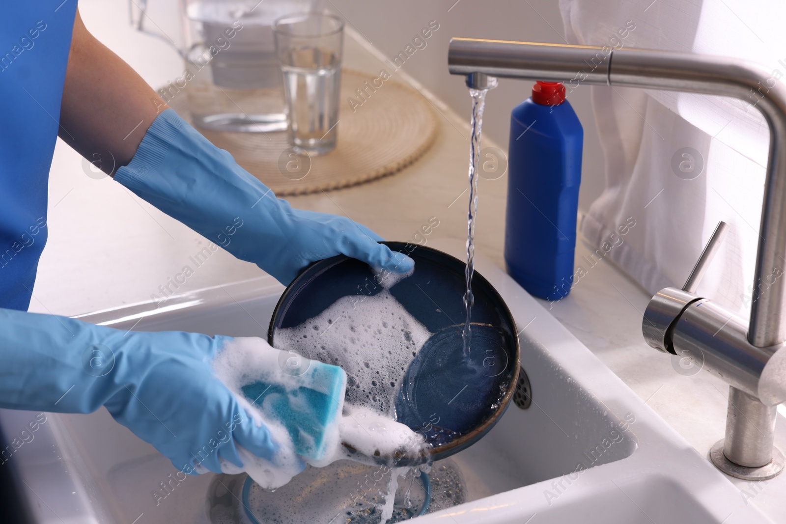 Photo of Woman washing dishes in kitchen sink, closeup