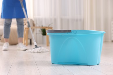 Photo of Woman cleaning floor with string mop indoors, focus on bucket