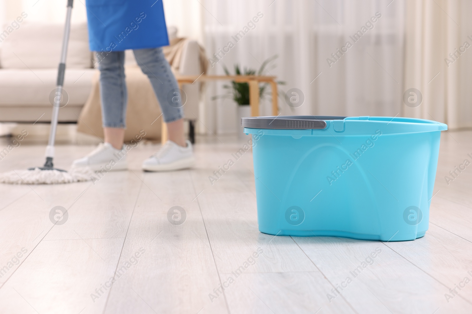 Photo of Woman cleaning floor with string mop indoors, focus on bucket