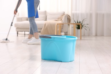 Photo of Woman cleaning floor with string mop indoors, focus on bucket