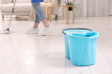 Photo of Woman cleaning floor with string mop indoors, focus on bucket