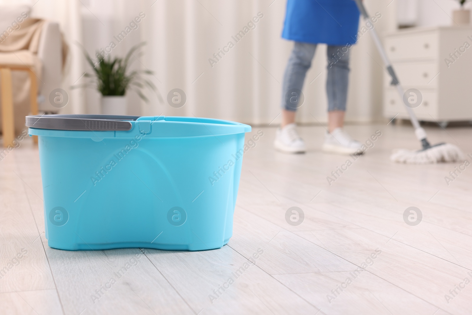 Photo of Woman cleaning floor with string mop indoors, focus on bucket