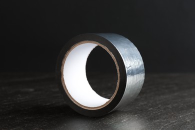 Photo of Roll of silver adhesive tape on black table, closeup