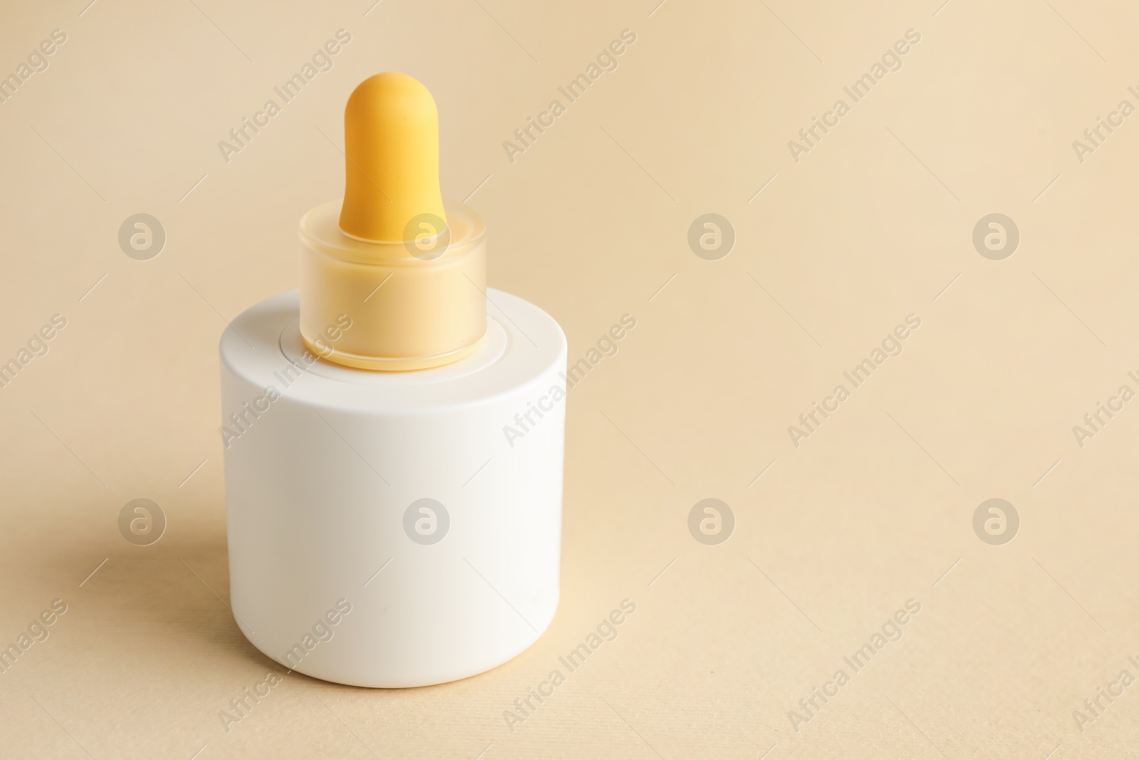 Photo of Bottle of skin care product on beige background, space for text