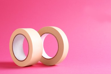 Photo of Two masking tapes on pink background, closeup. Space for text