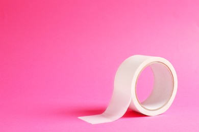 One masking tape on pink background, closeup. Space for text