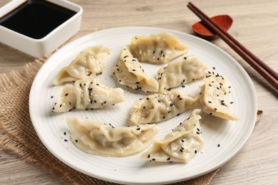 Photo of Delicious gyoza dumplings with sesame seeds served on wooden table, closeup