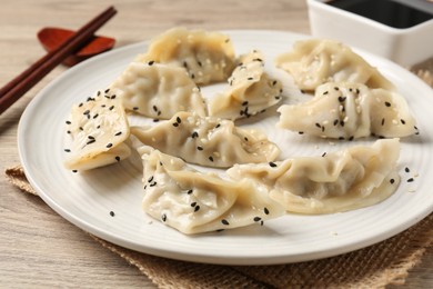 Photo of Delicious gyoza dumplings with sesame seeds served on wooden table, closeup