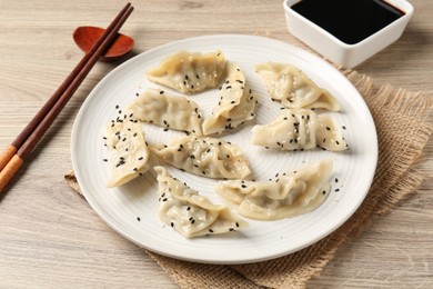 Photo of Delicious gyoza dumplings with sesame seeds served on wooden table, closeup