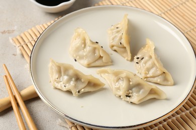 Photo of Delicious gyoza dumplings with sesame seeds served on light table, closeup