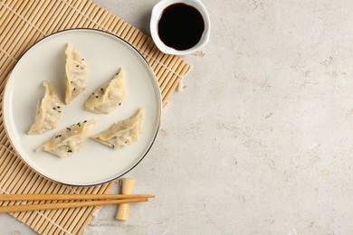 Photo of Delicious gyoza dumplings with sesame seeds served on light table, top view. Space for text