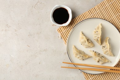 Photo of Delicious gyoza dumplings with sesame seeds served on light table, top view. Space for text