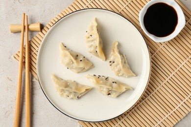 Photo of Delicious gyoza dumplings with sesame seeds served on light table, top view