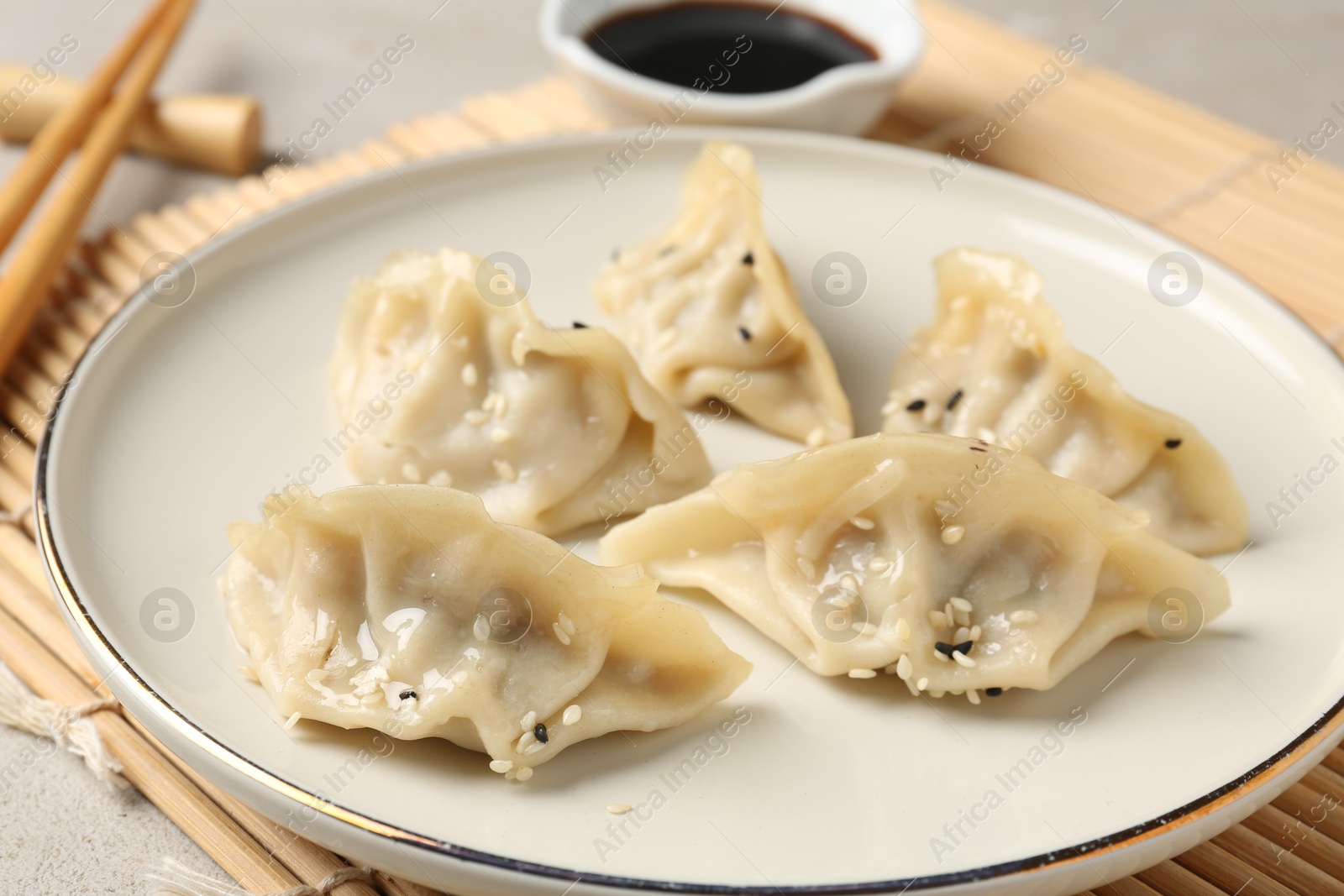 Photo of Delicious gyoza dumplings with sesame seeds served on light table, closeup