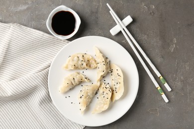 Photo of Delicious gyoza dumplings with sesame seeds served on grey table, top view