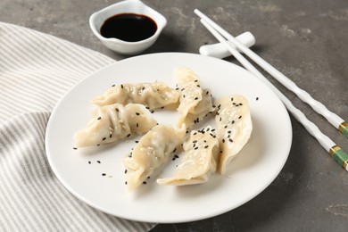 Photo of Delicious gyoza dumplings with sesame seeds served on grey table, closeup