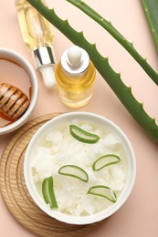 Photo of Hair treatment. Coconut, butter shavings, honey, cosmetic product and aloe leaves on beige background, flat lay