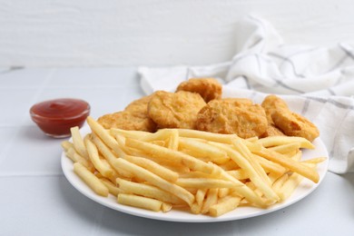 Photo of Tasty chicken nuggets and french fries with sauce on white tiled table, closeup