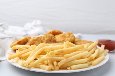 Photo of Tasty chicken nuggets and french fries with sauce on white tiled table, closeup. Space for text
