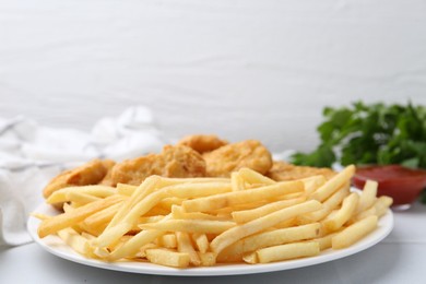 Photo of Tasty chicken nuggets and french fries with sauce on white tiled table, closeup. Space for text